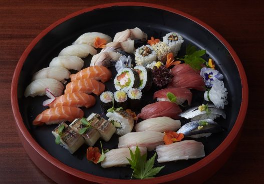 Sushi nigiri and maki selection in a Japanese sushi oke (container).